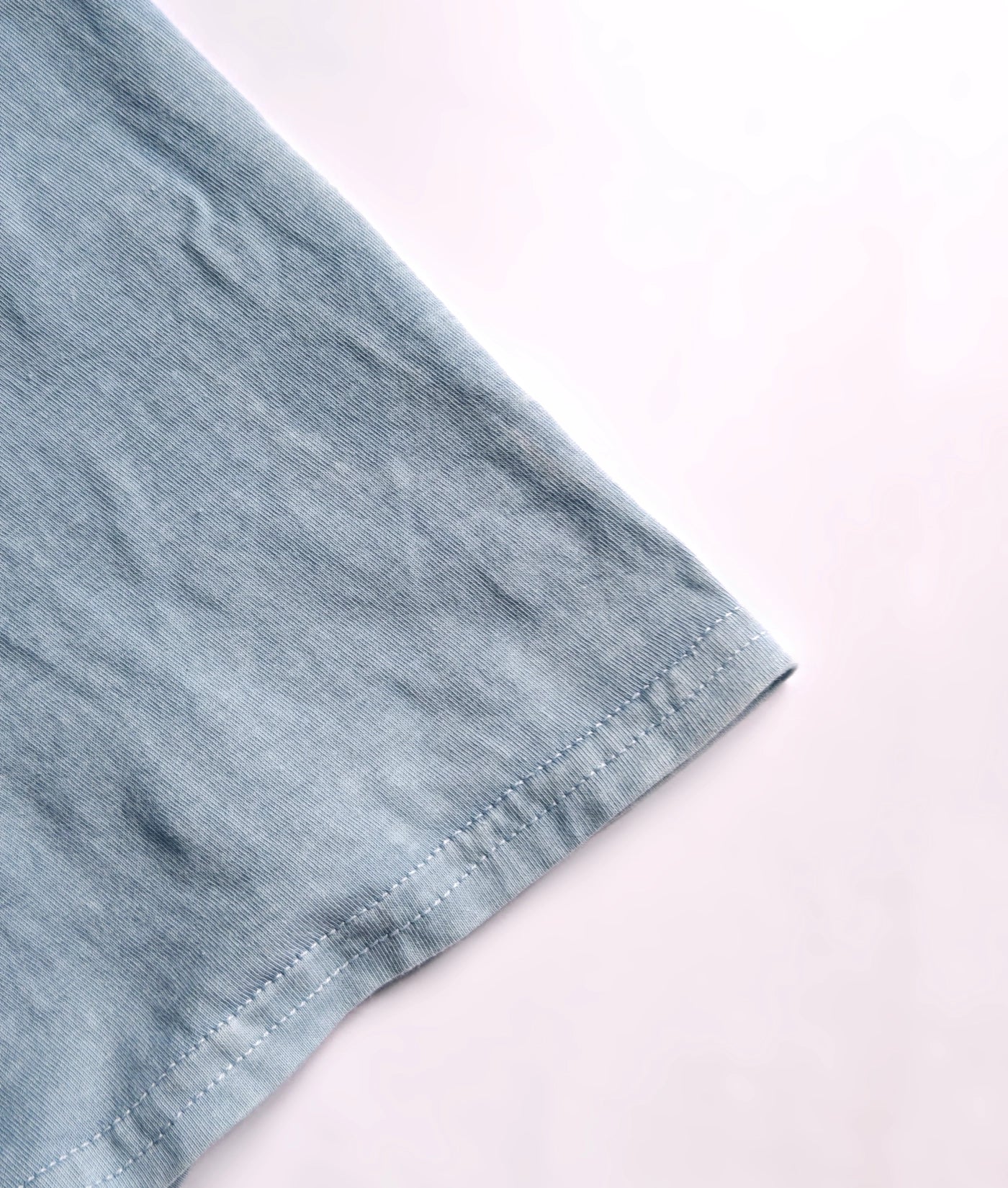 Detail of stitched hem on natural indigo dyed organic cotton T-shirt.