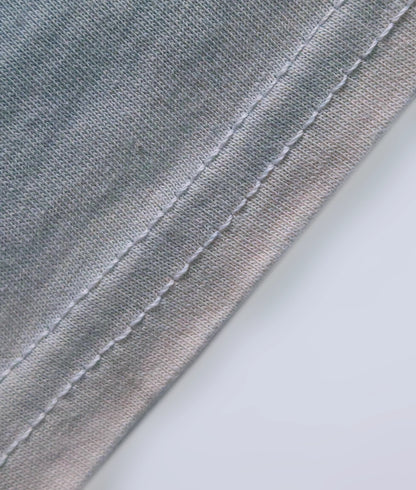 Detail of stitched hem on a natural indigo dyed organic cotton T-shirt.