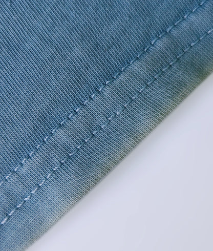 Detail of stitched hem on a natural indigo dyed organic cotton T-shirt.