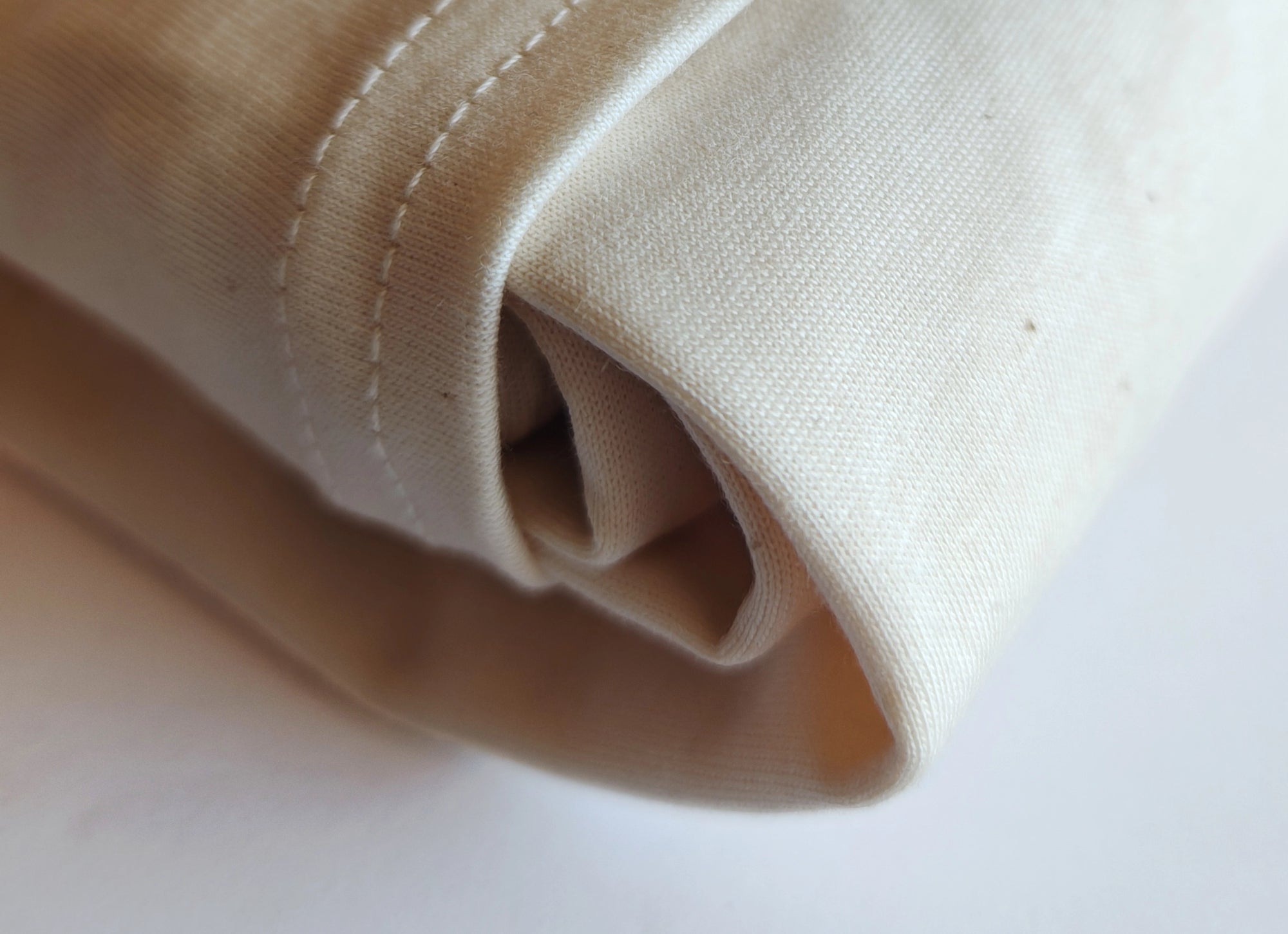 Detail of organic cotton T-shirt jersey fabric, highlighting soft natural texture.