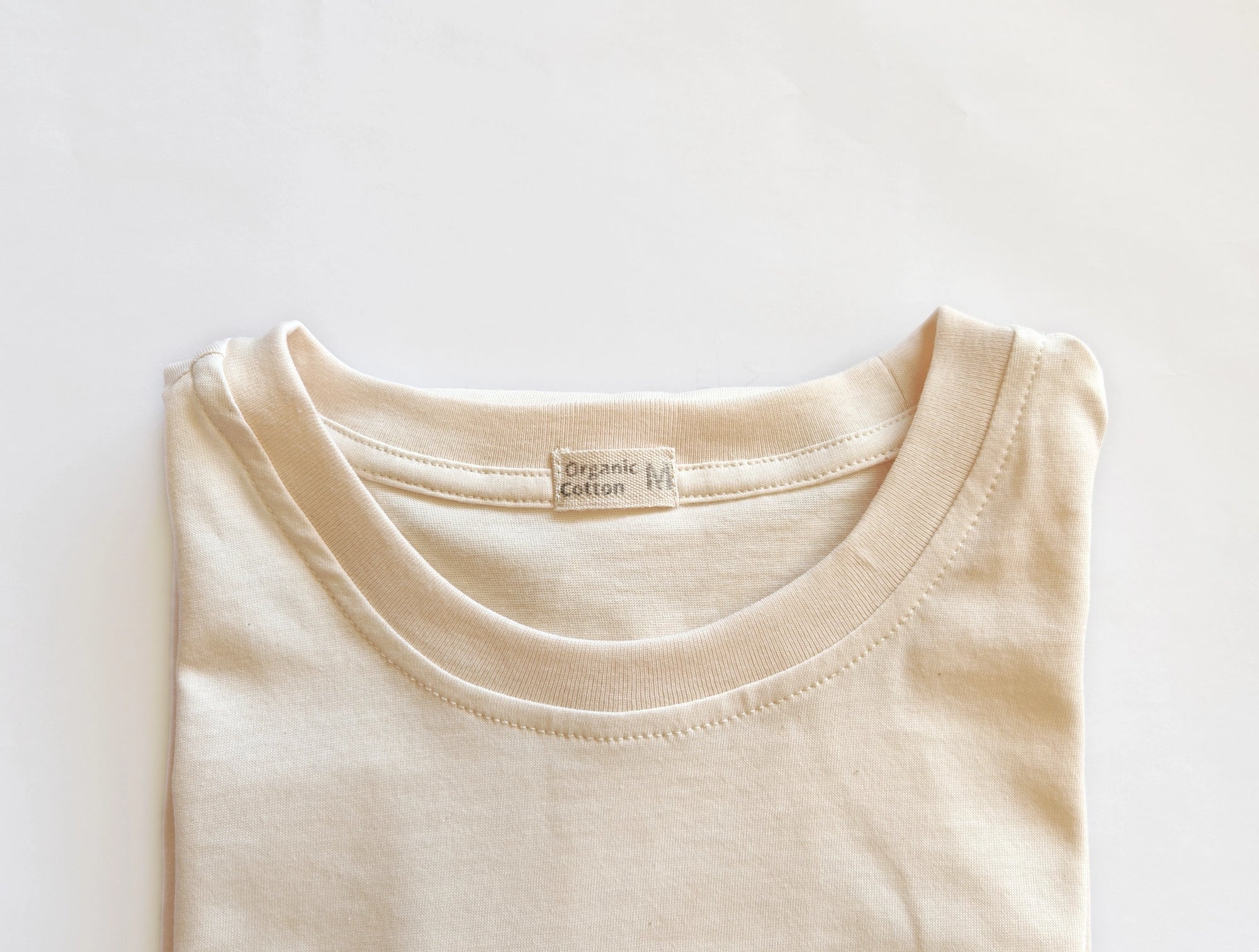 Close-up of ribbed neckline on an unbleached, undyed organic cotton T-shirt.